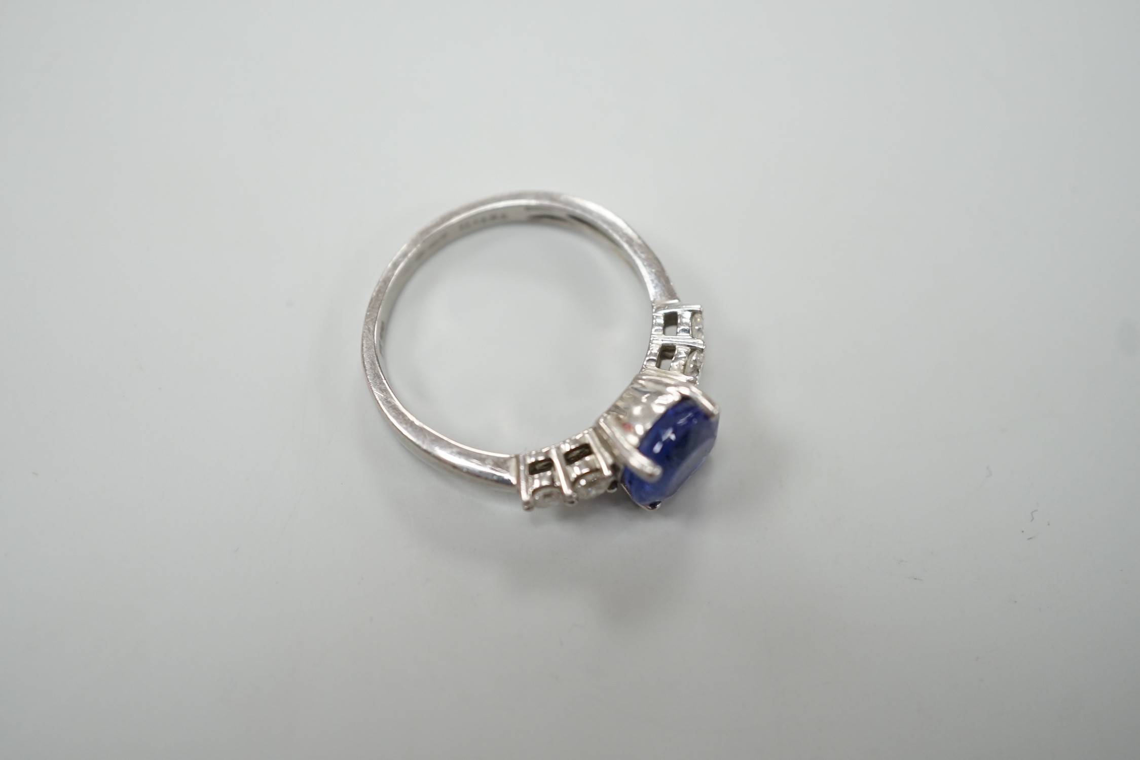 A modern Illiana platinum, single stone round cut tanzanite and four stone diamond set dress ring, size O, gross weight 5.7 grams.